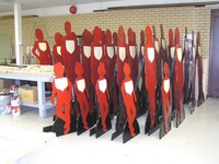 Figures for the Silent Witness Project, which represent victims of domestic violence. They are all red and are shaped as women, men, and children. The figures are leaning against a table. 